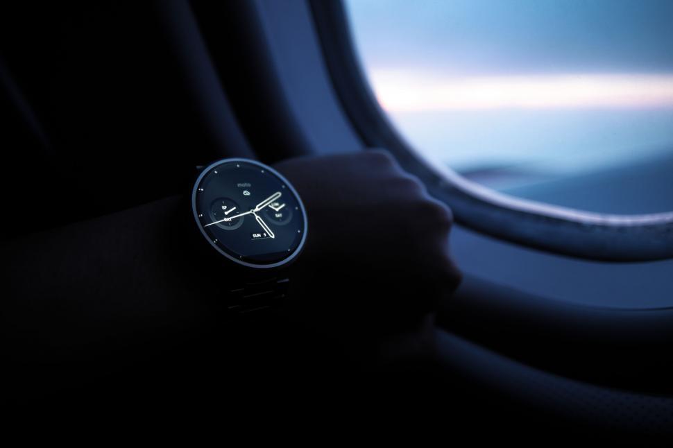 Free Image of Wristwatch on arm against airplane window view 