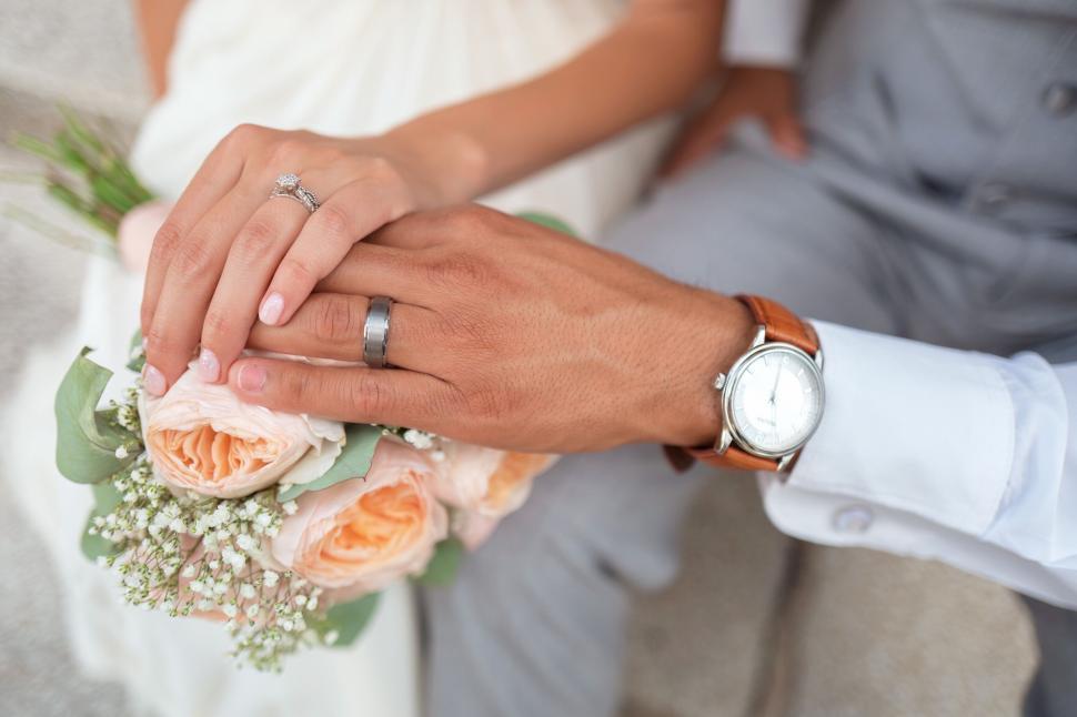 Free Image of Close-up of wedding hands with rings and flowers 