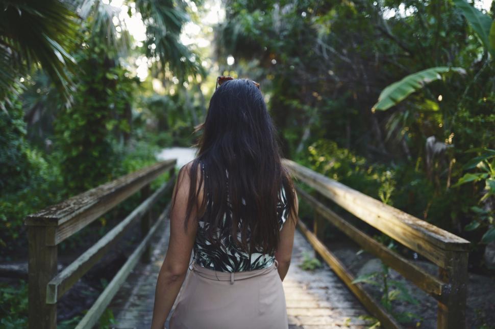 Free Image of Woman walking on a wooden bridge in the forest 