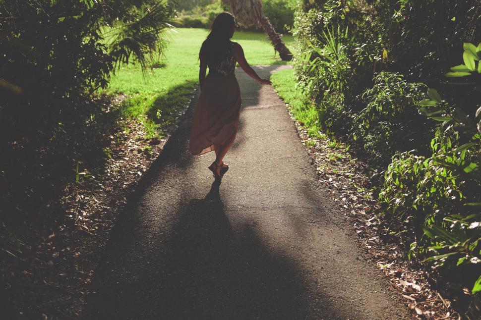 Free Image of Woman walking down a path among trees 
