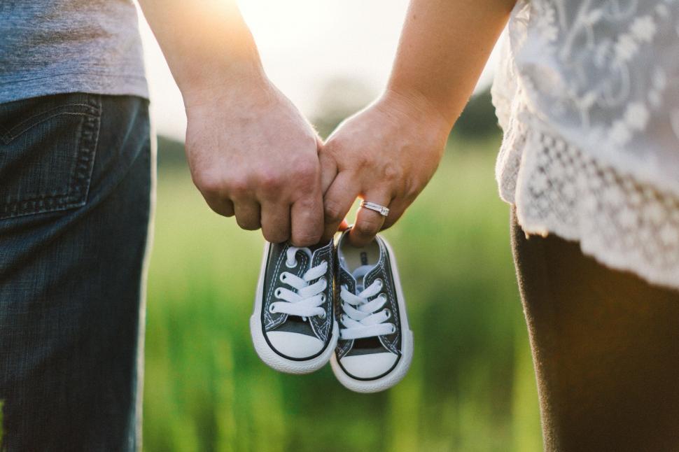 Free Image of Couple holding hands with baby shoes 