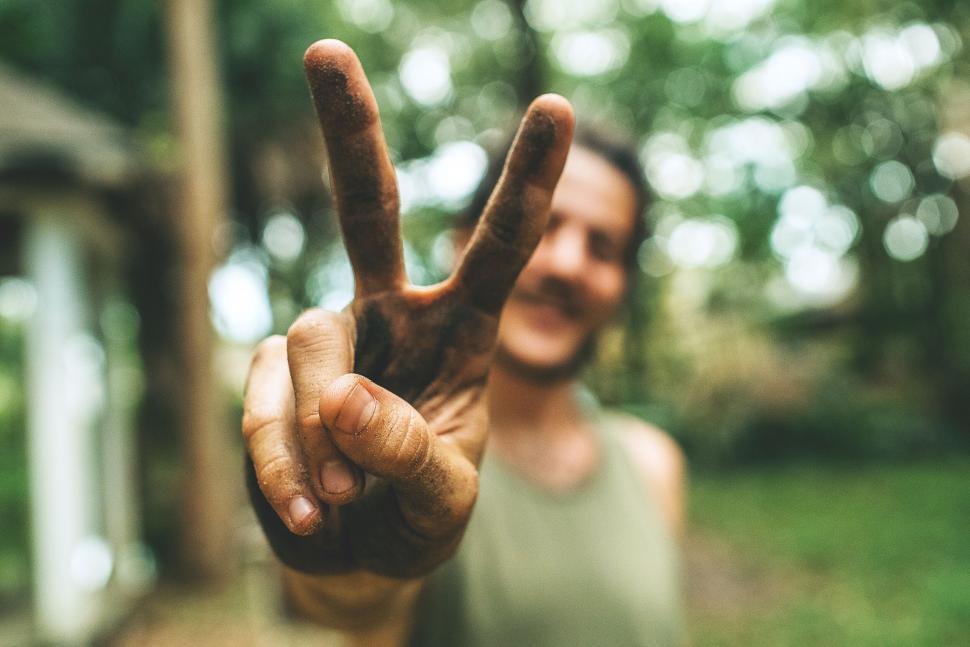 Free Image of Man showing peace sign with dirty hands face blurred 