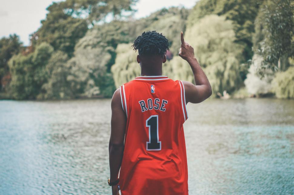 Free Image of Man in Derrick Rose jersey overlooking a lake 