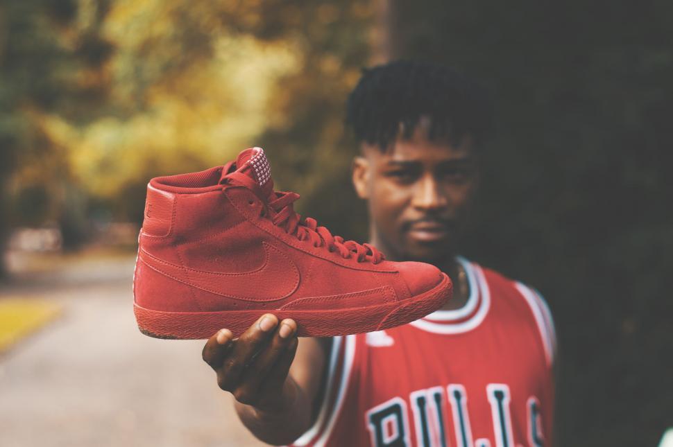 Free Image of Man holding red sneaker in focus 