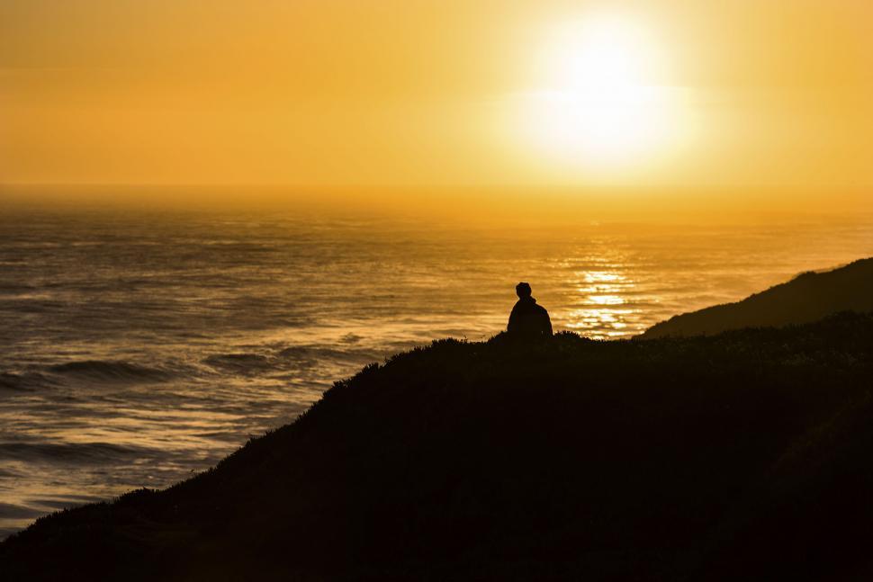 Free Image of Silhouette of person at sunset by the ocean 