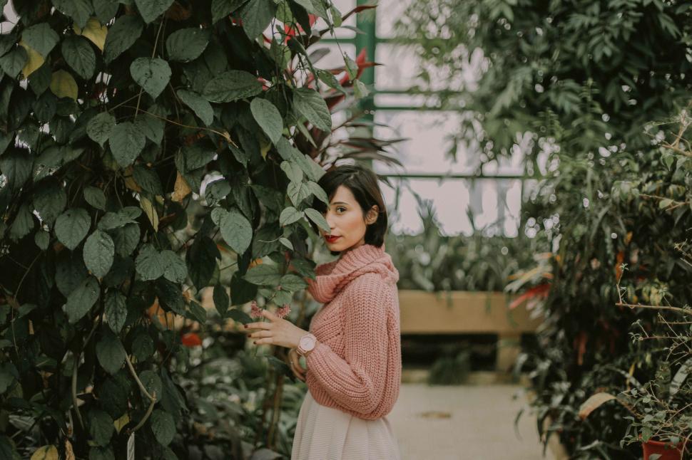 Free Image of Woman in pink sweater among greenery 