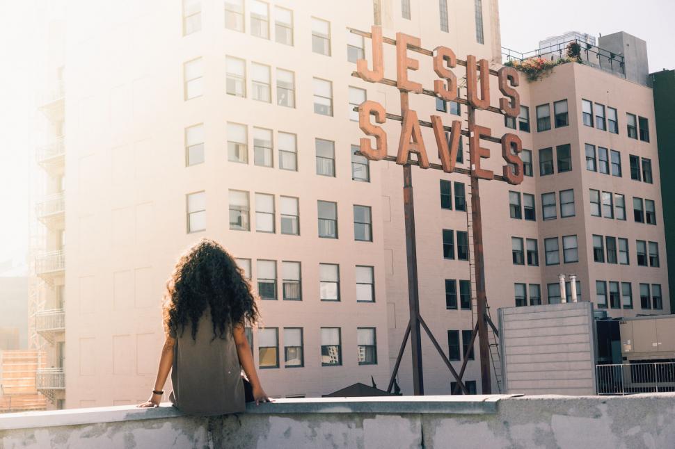 Free Image of Woman overlooking city with Jesus Saves sign 