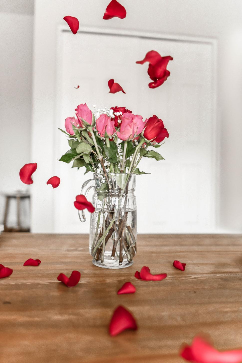 Free Image of Flowers and rose petals on a wooden table 