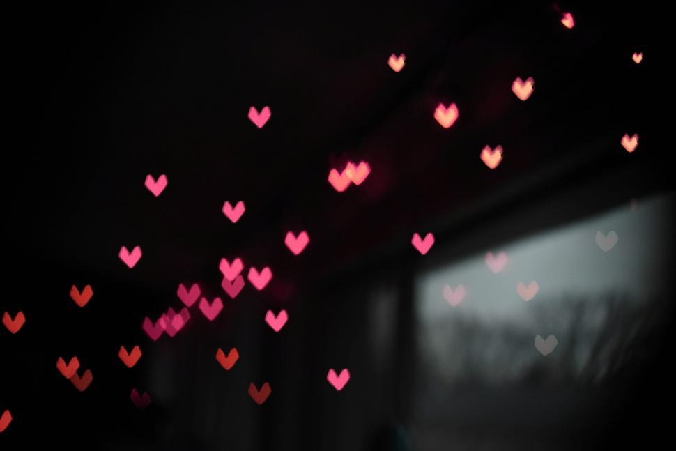 Free Image of Bokeh hearts illuminating a dark background 