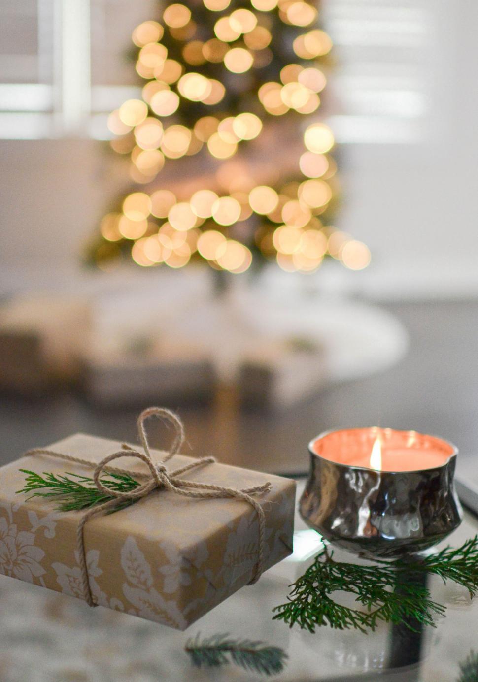 Free Image of Gift and candle with Christmas tree in background 