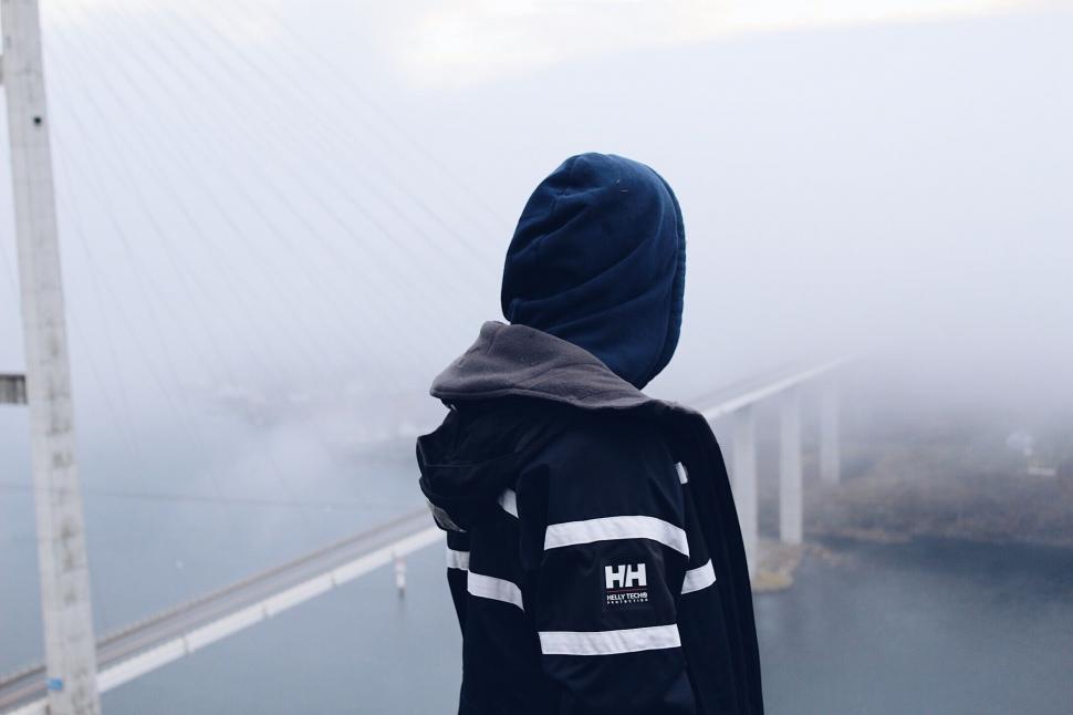 Free Image of Back view of a person overlooking a foggy bridge 