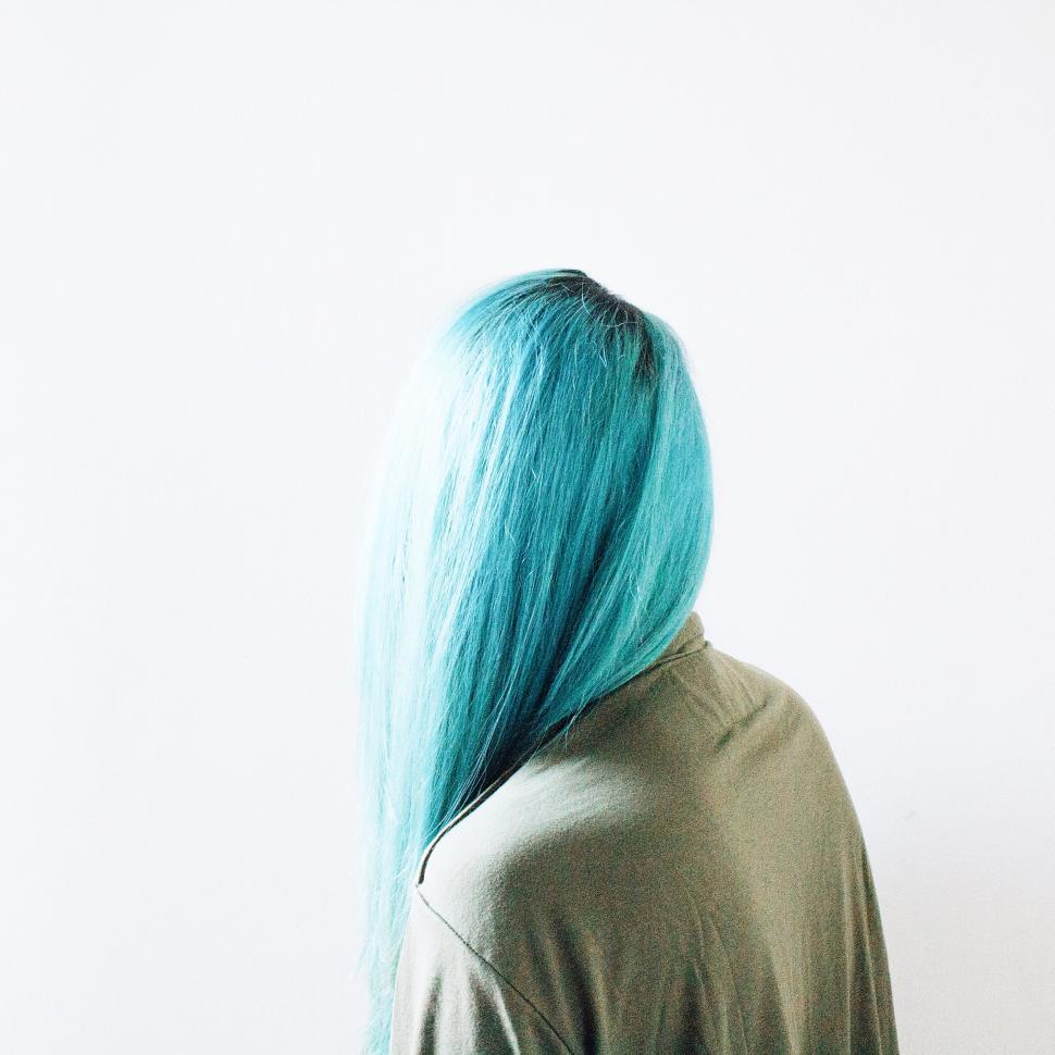 Free Image of Person with turquoise hair facing a blank wall 