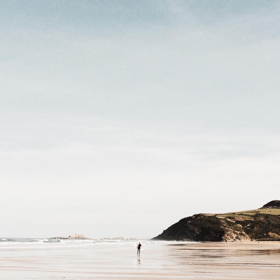 Free Image of Lonely figure walking on a peaceful beach 
