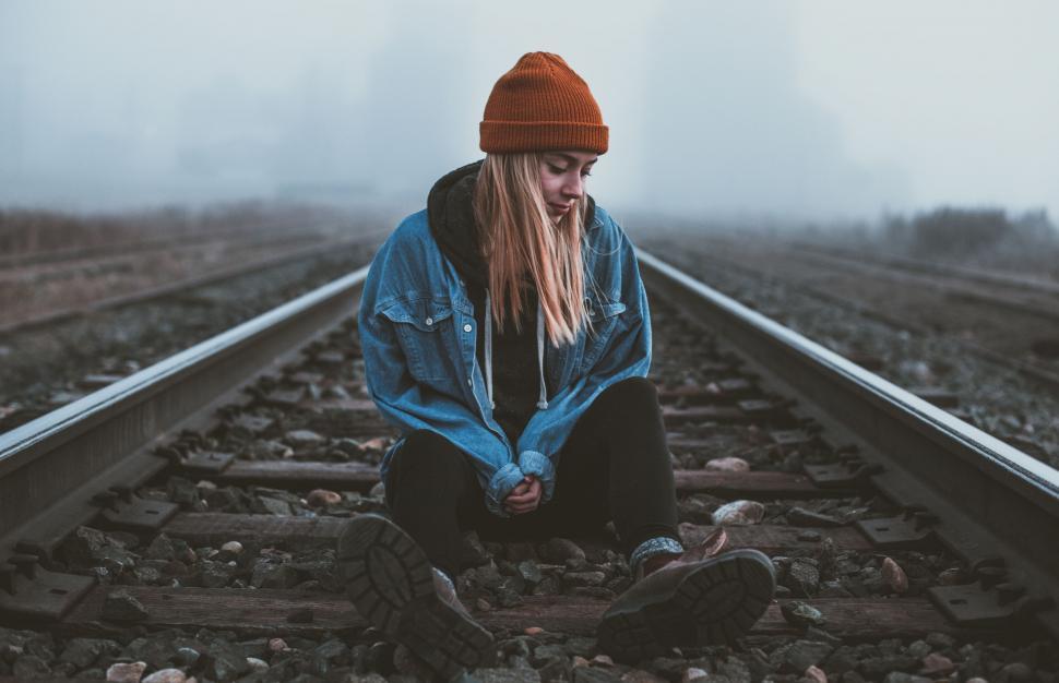 Free Image of Person sitting on foggy railroad tracks 
