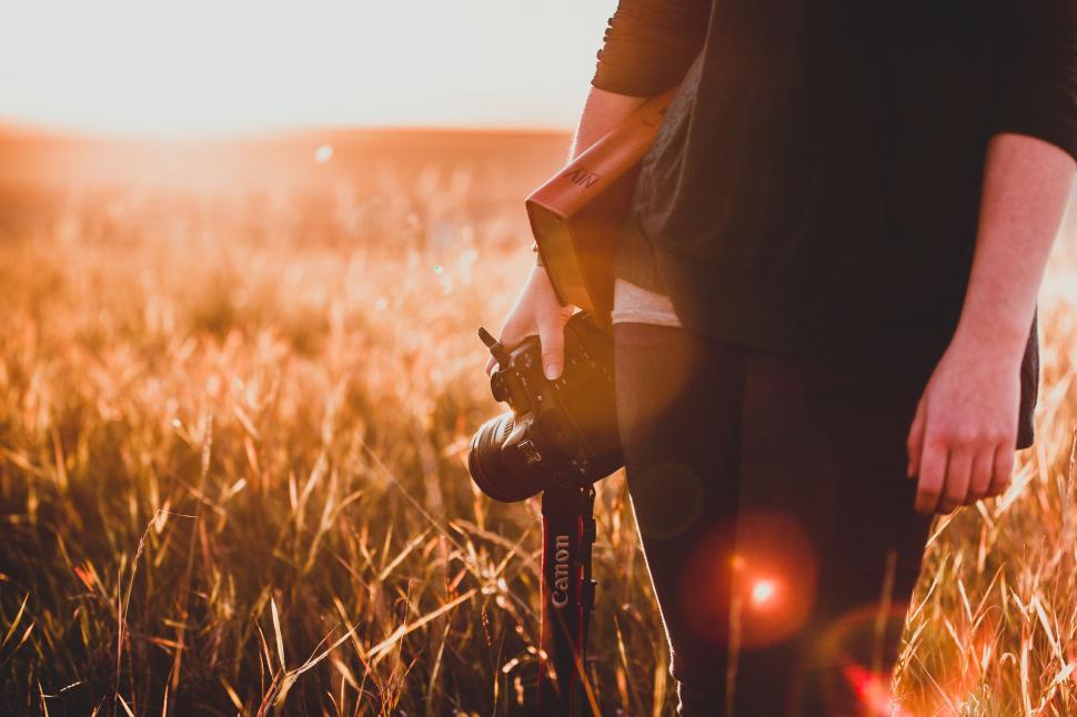 Free Image of Photographer holding a camera in a field 