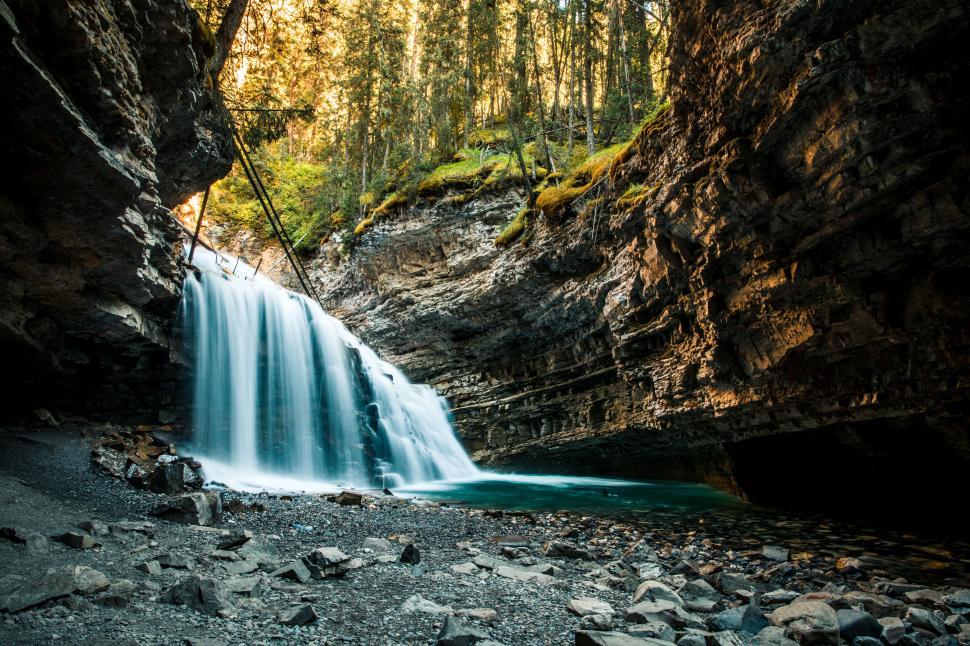 Free Image of Majestic waterfall in a serene forest cave 