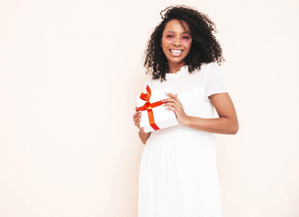 Free Image of A woman in a white dress holding a gift 