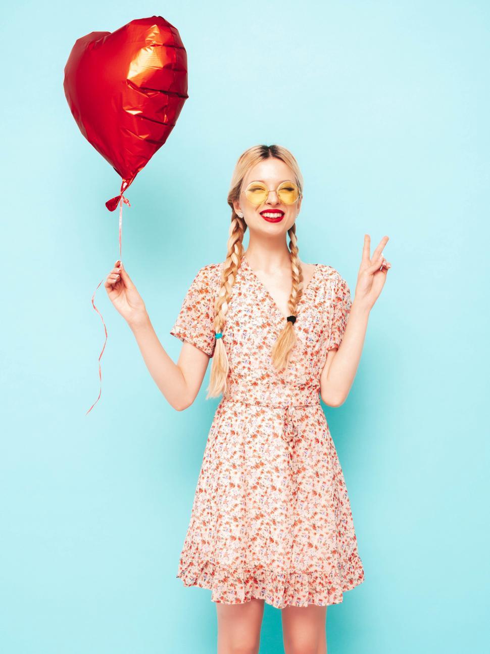 Free Image of A woman holding a heart shaped balloon 