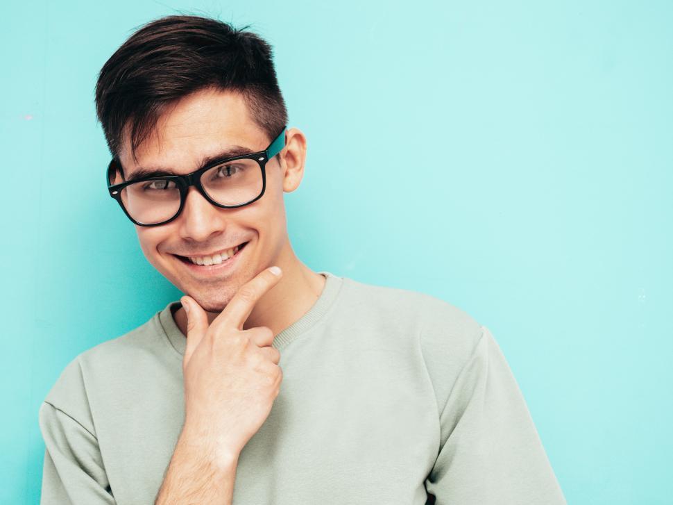 Free Image of A man wearing glasses and touching his chin 