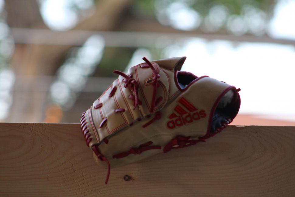 Free Image of Adidas baseball glove resting on wooden surface 