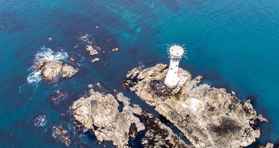 Free Image of Aerial view of lighthouse on rugged coastline 