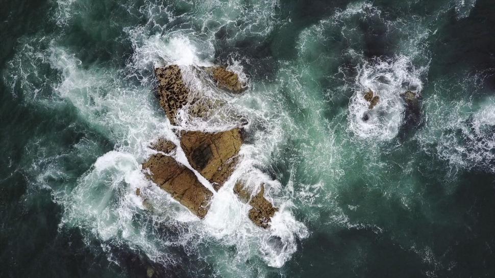 Free Image of Aerial view of waves crashing on rocks 