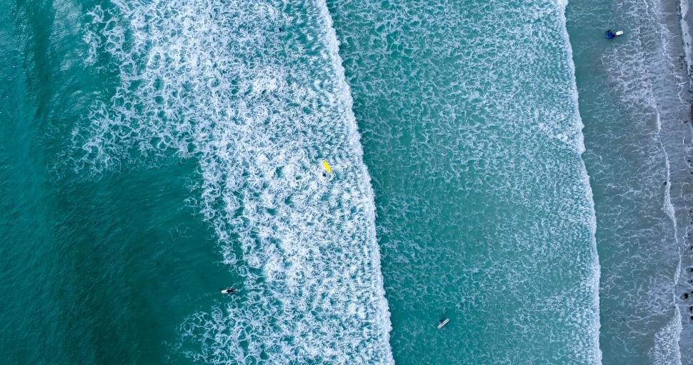 Free Image of Aerial view of surfers on a wavy sea surface 