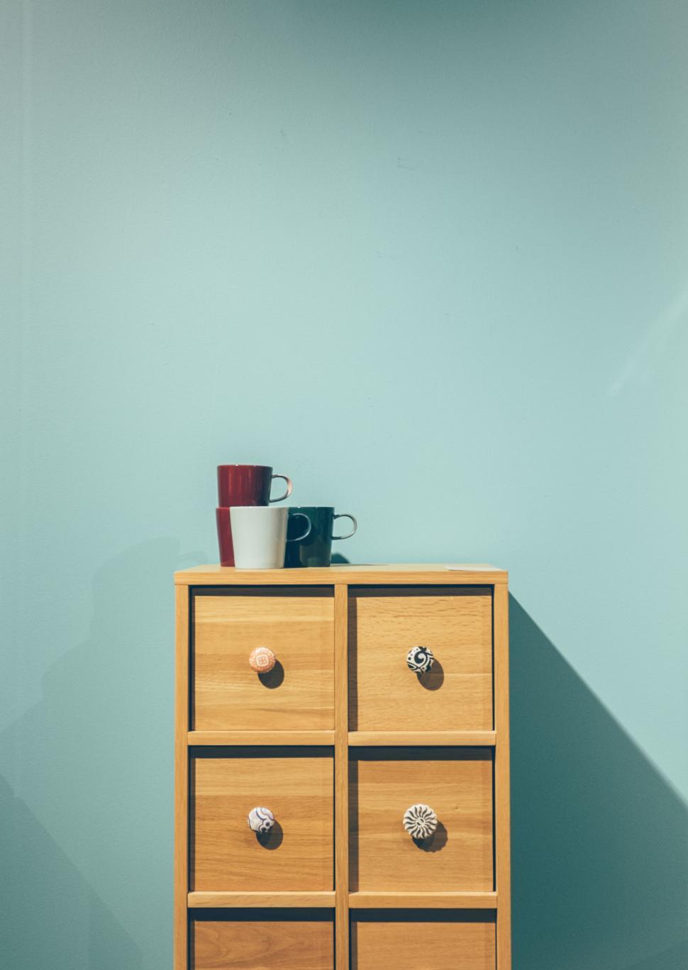 Free Image of Minimalist wooden cabinet with colorful mugs 