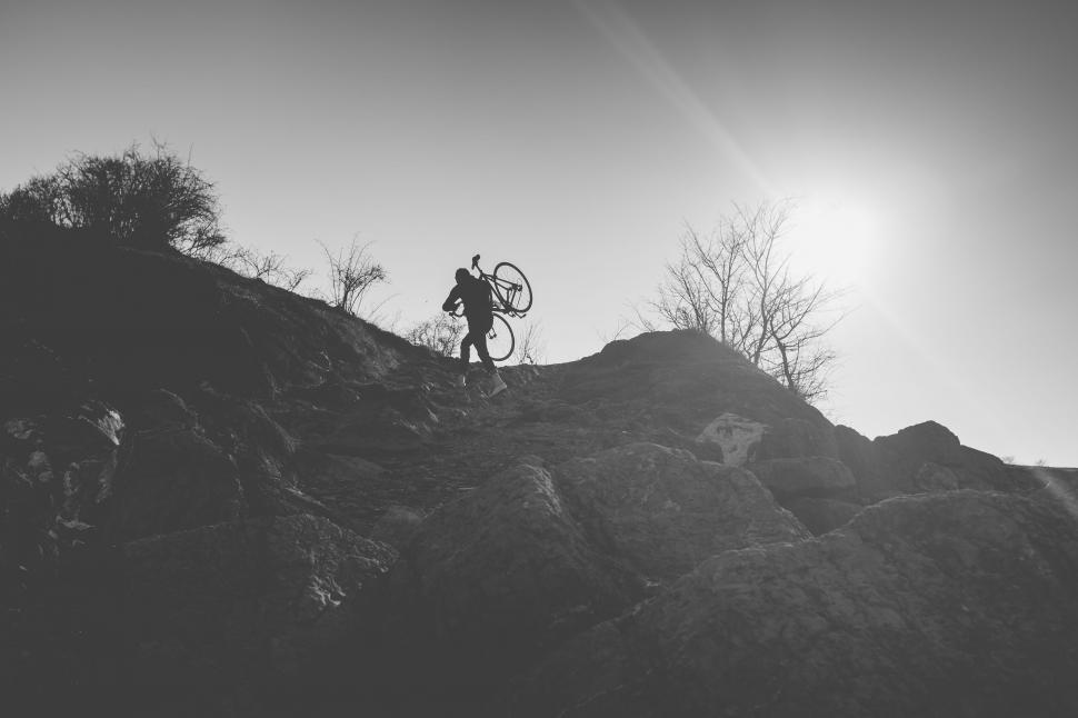 Free Image of Cyclist carrying bike uphill silhouette style 