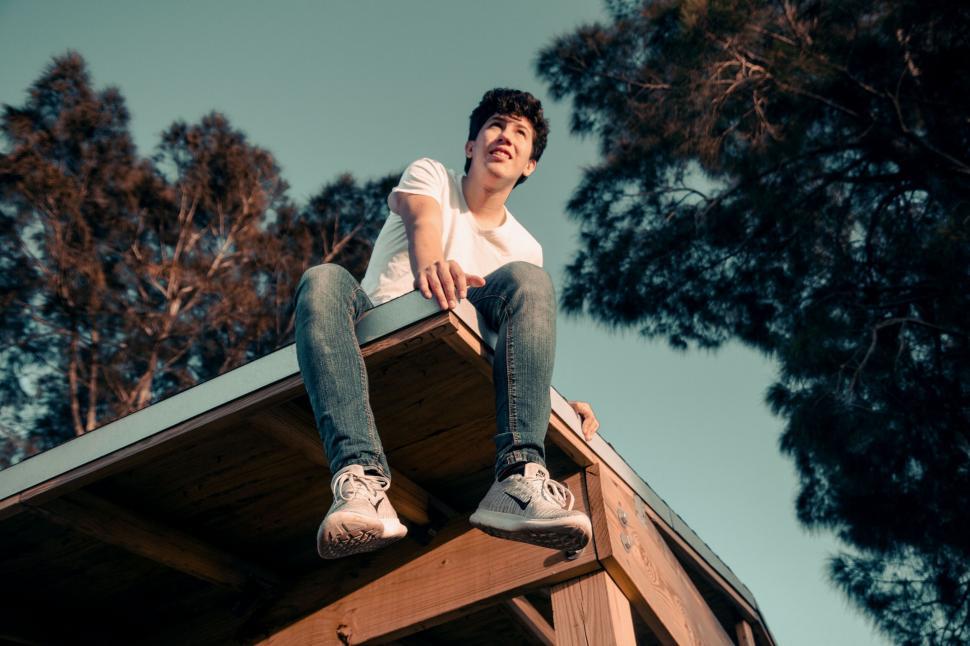 Free Image of Young man sitting high on a rooftop 