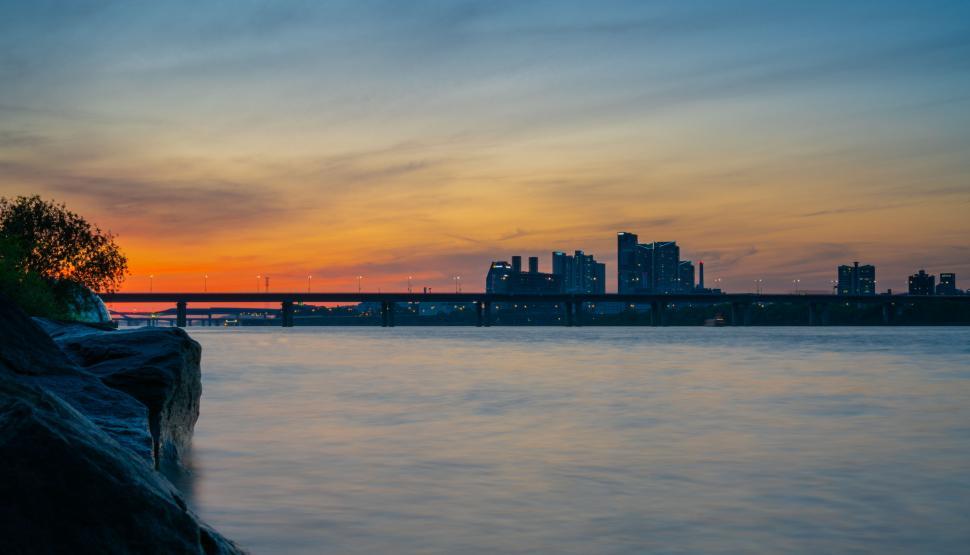 Free Image of Riverside sunset with silhouette buildings 