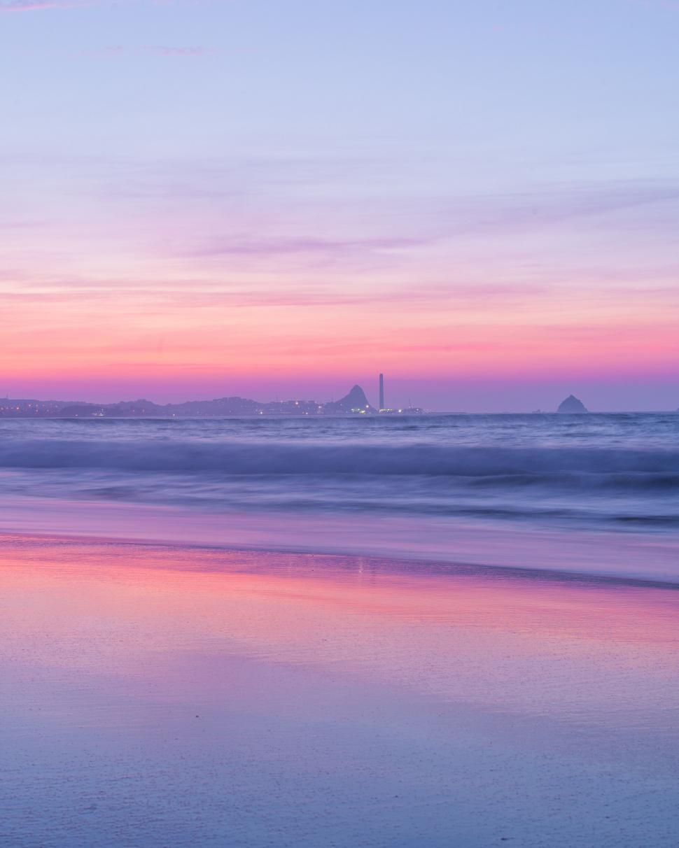 Free Image of Pastel sunset over the ocean with city view 