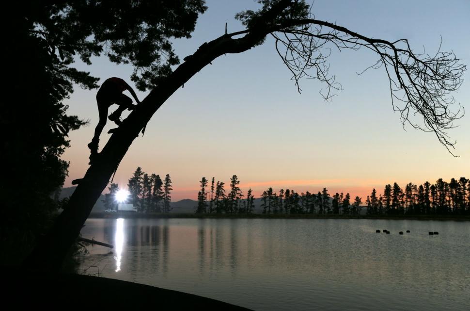 Free Image of Rock climber silhouette over tranquil sunset lake 