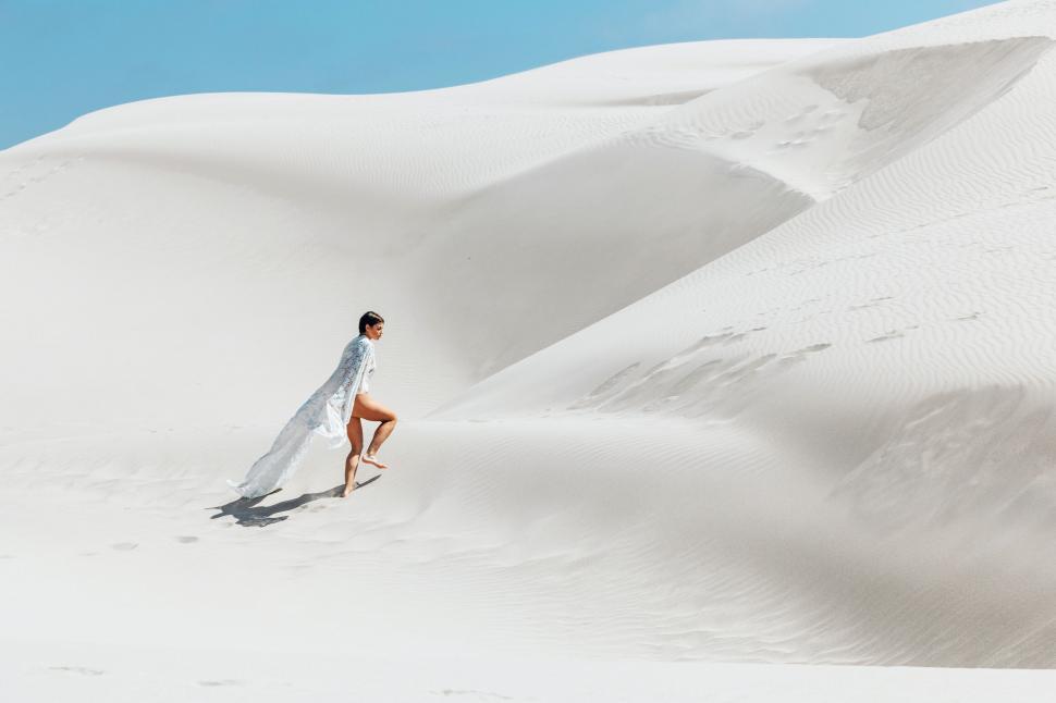 Free Image of Woman walking on vast sand dunes 