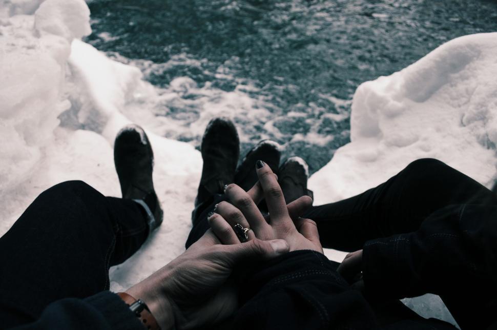 Free Image of Couple holding hands by icy waters 