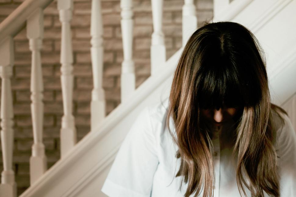 Free Image of Woman sitting on stairs with obscured face 