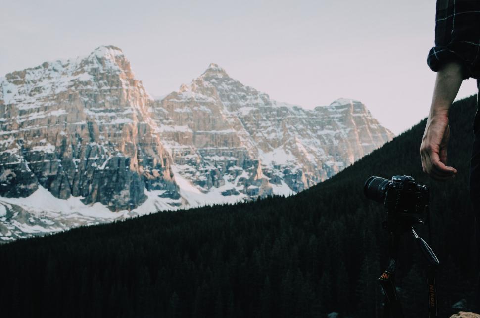 Free Image of Person setting up camera with mountain backdrop 