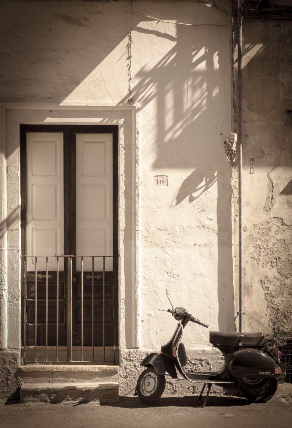 Free Image of Vintage scooter parked by weathered door 