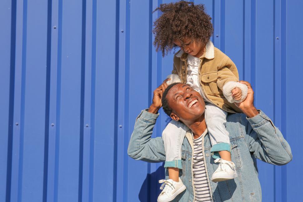Free Image of Child on shoulders against a blue wall 