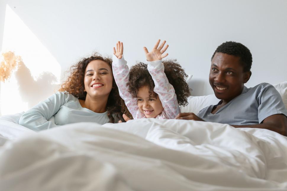 Free Image of Happy family with hands raised in bed 