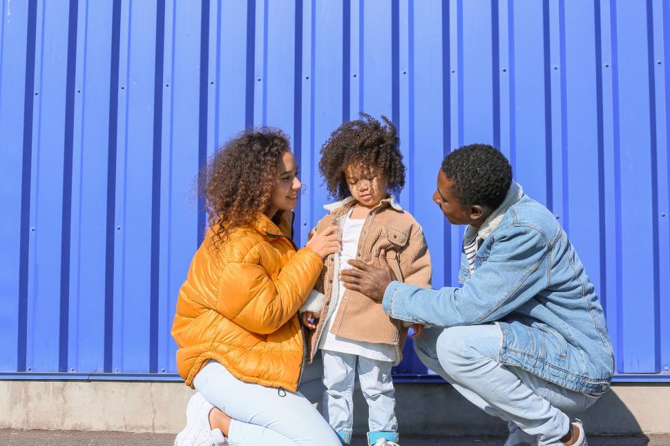 Free Image of Family with young daughter against blue wall 