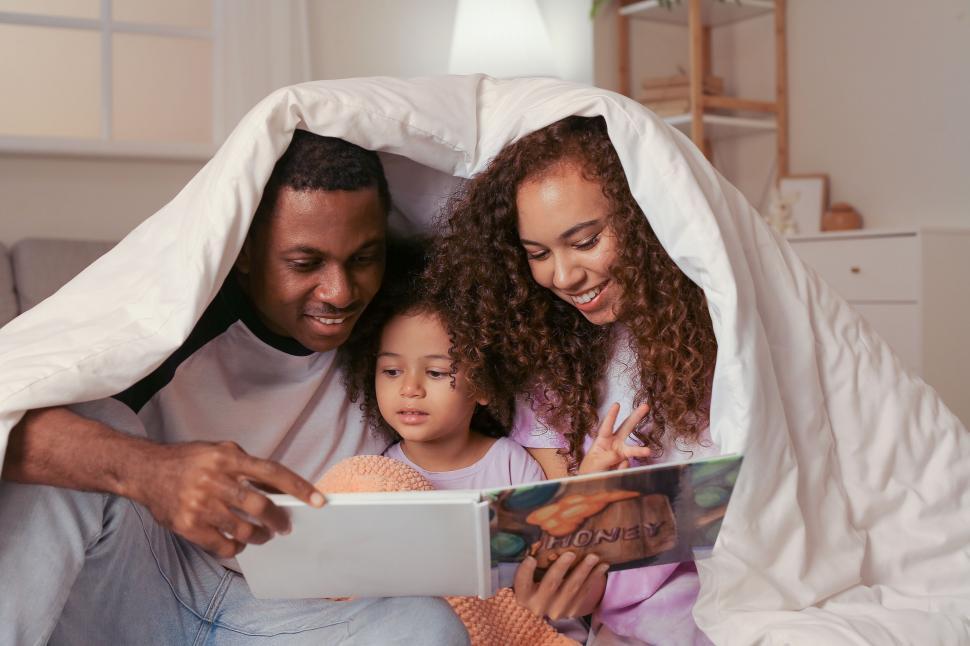 Free Image of Playful family reading under the covers at home 