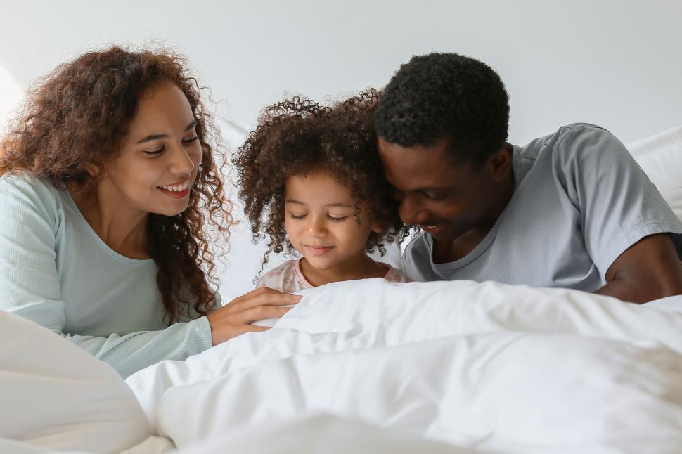 Free Image of Family cuddling in bed looking at a book 