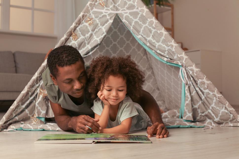 Free Image of Father and child enjoying a book in a tent 