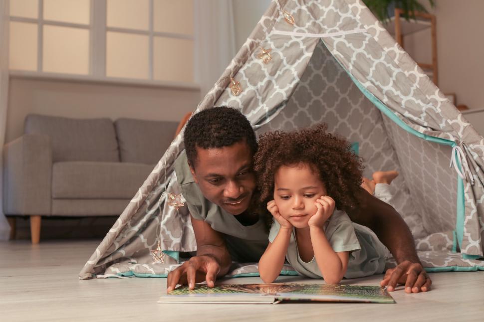 Free Image of Father and child reading under indoor tent 