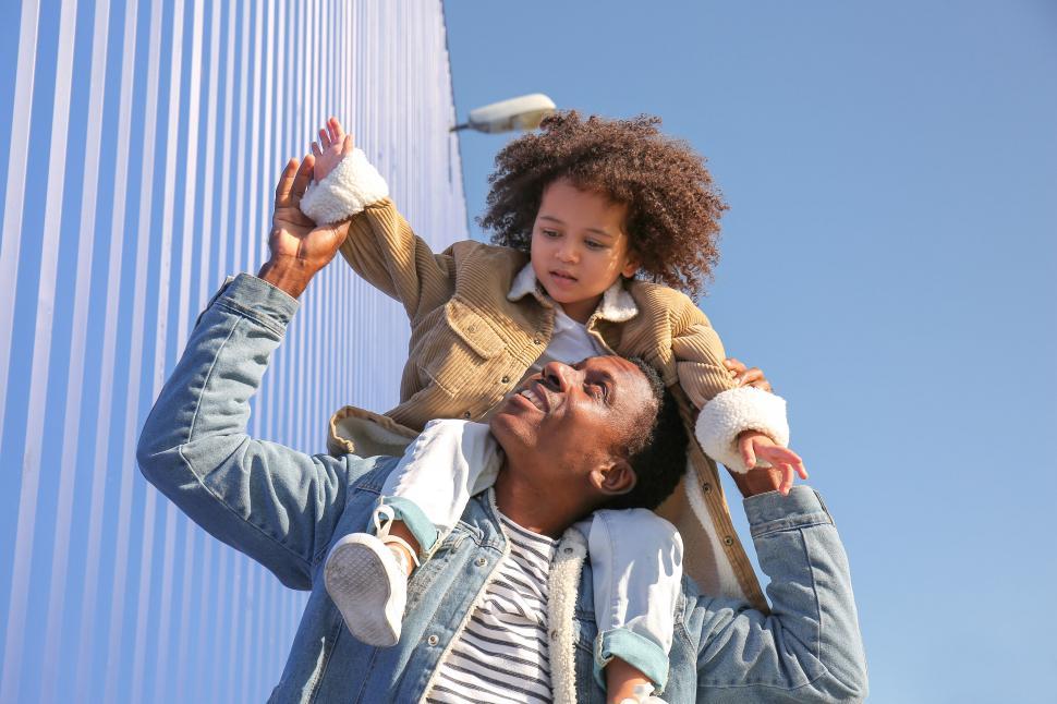 Free Image of Father lifting child high against blue sky 