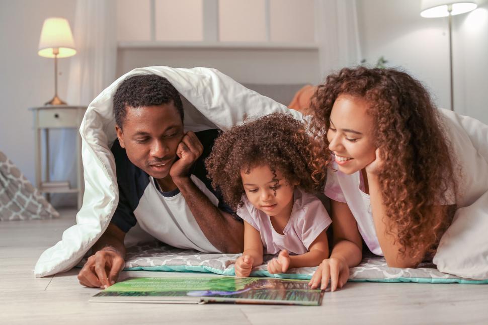 Free Image of Family reading a book under blanket 