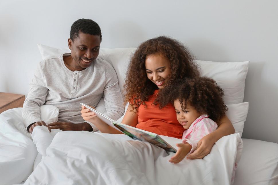Free Image of Parents reading to child in bed 