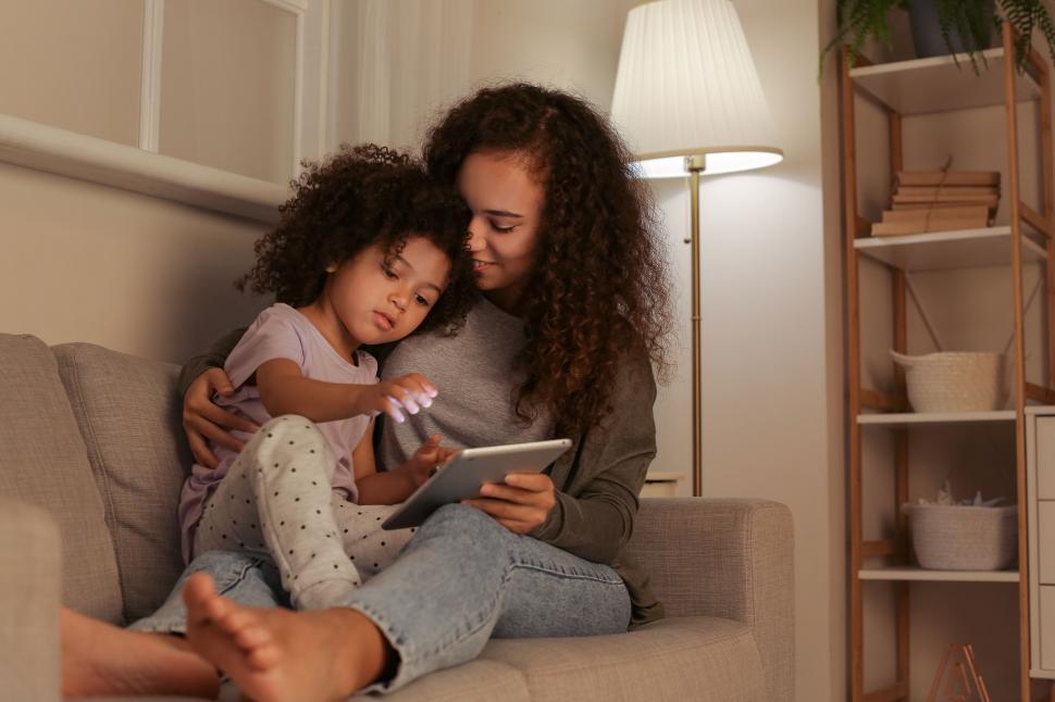 Free Image of Mother and daughter using tablet on sofa 