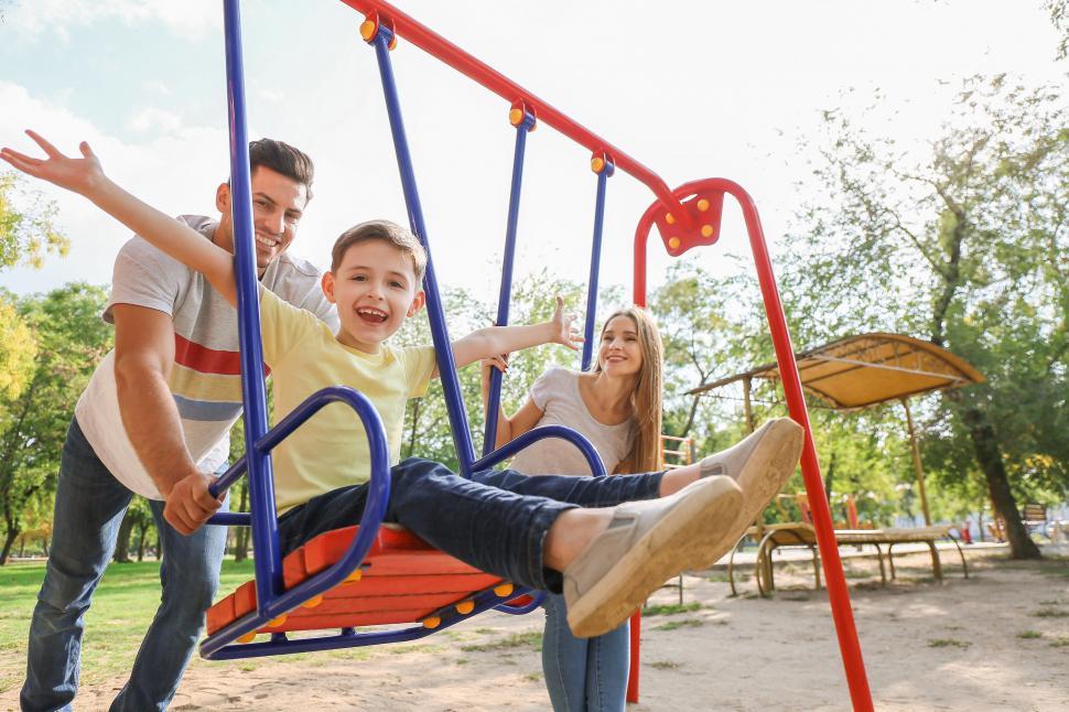 Free Image of Parents play swing with son at playground 